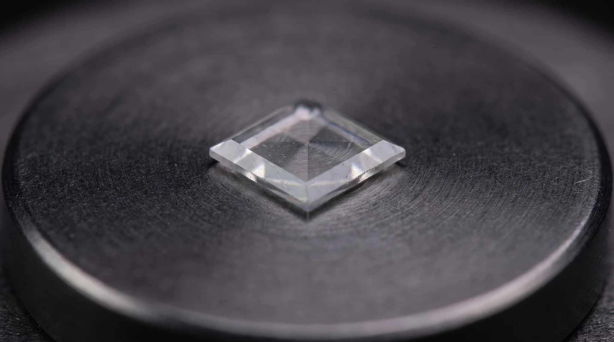 A small square diamond plate resting on a dark sample holder.
