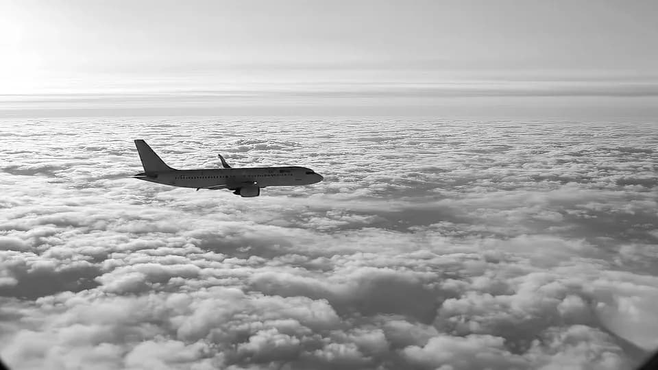 An airliner flying above a layer of cloud.